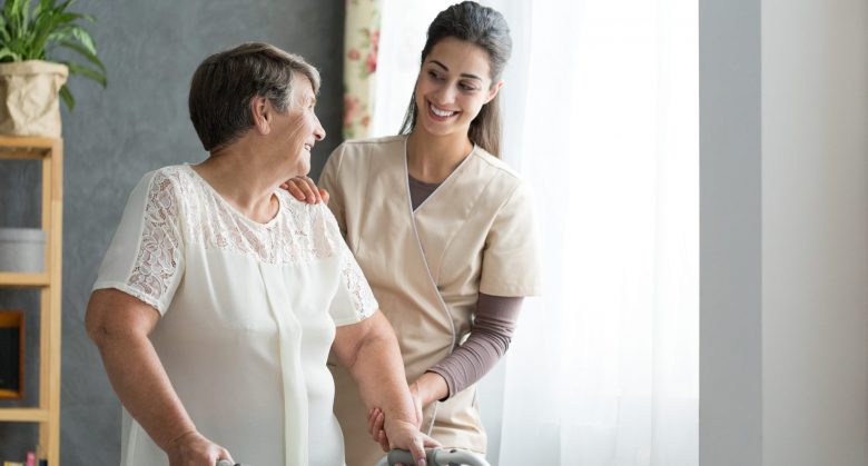 Smiling nurse helping senior lady to walk around the nursing home.