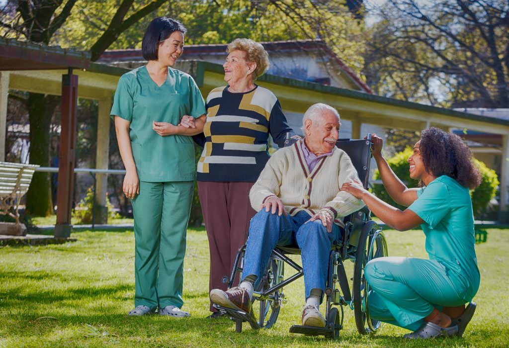 Homecare workers with elderly couple outside.